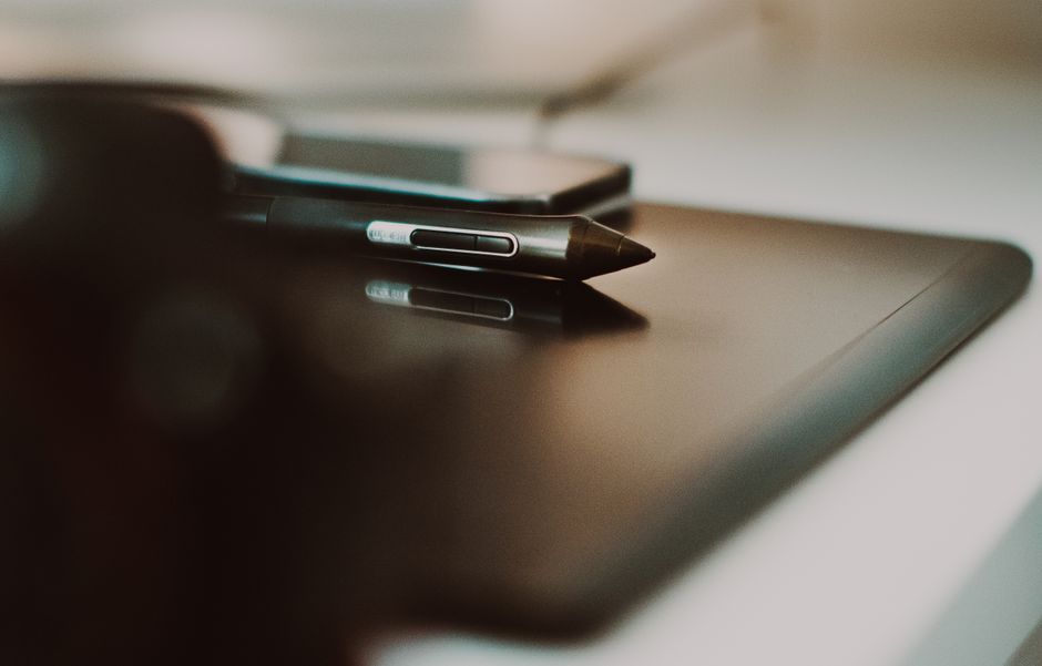 Imagem de um telefone e uma caneta sobre uma mesa, simbolizando o trabalho remoto e a comunicação digital em ambientes profissionais.
