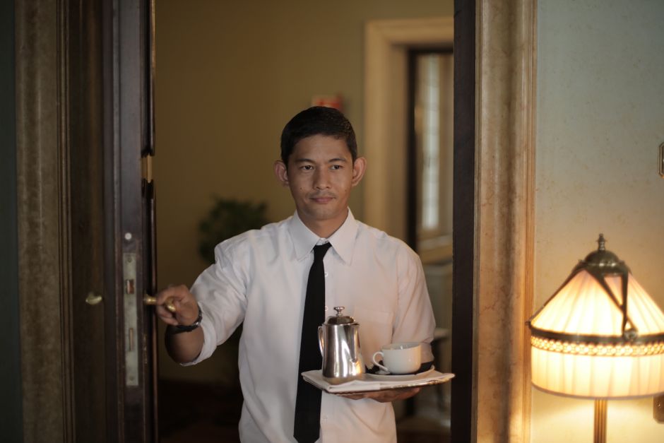 Garçom servindo café em um ambiente de hotel ou restaurante, transmitindo acolhimento e atendimento ao cliente.