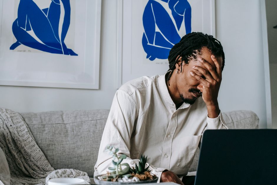 Homem preocupado com problemas ou dificuldades enquanto trabalha no computador, em um ambiente de casa ou escritório.