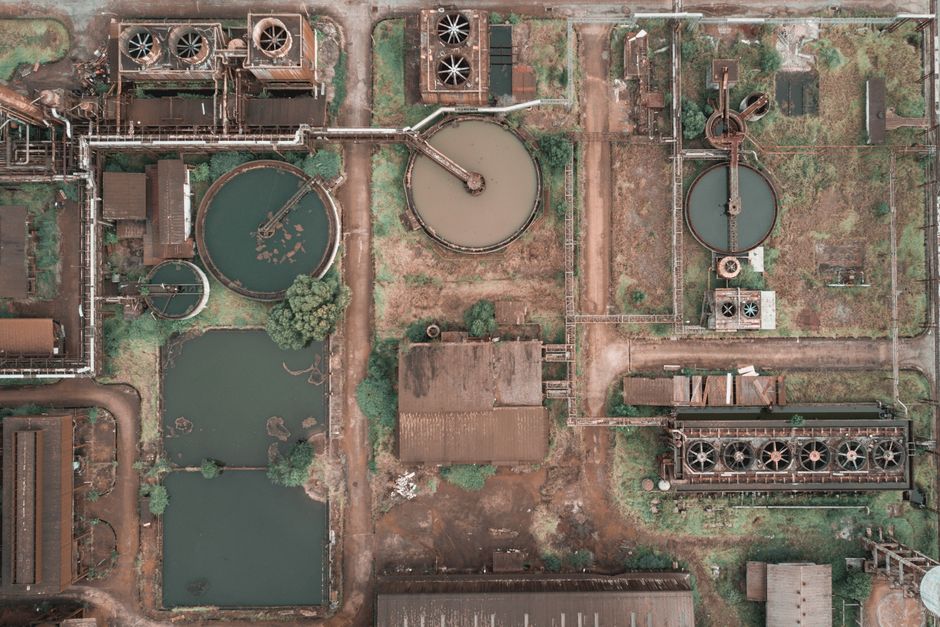 Imagem aérea de uma usina de tratamento de água ou efluentes com estruturas de tanques e sistemas de ventilação, destacando a infraestrutura industrial de saneamento básico.