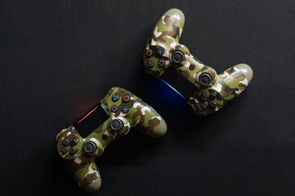 Dois controles de videogame com design de camuflagem em fundo escuro, destacando o tema de jogos eletrônicos e entretenimento digital.