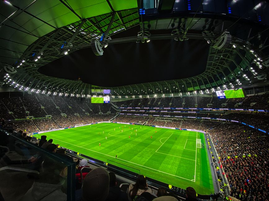 Estádio de futebol lotado com jogo em andamento sob iluminação intensa durante a noite, ideal para artigos sobre esportes e eventos ao vivo.