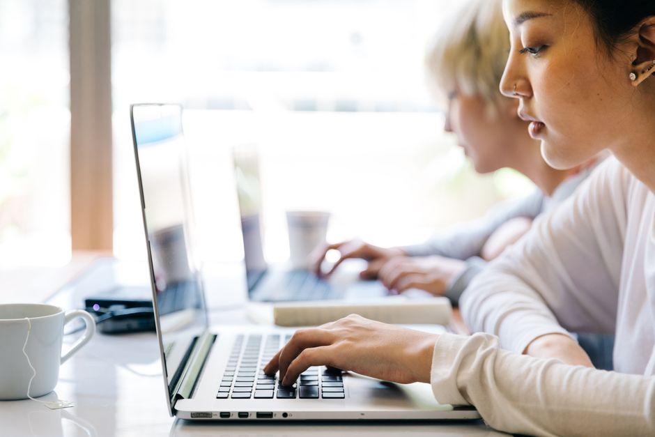 Mulheres concentradas trabalhando em laptops durante uma reunião ou estudo, simbolizando foco e produtividade em ambiente de trabalho.