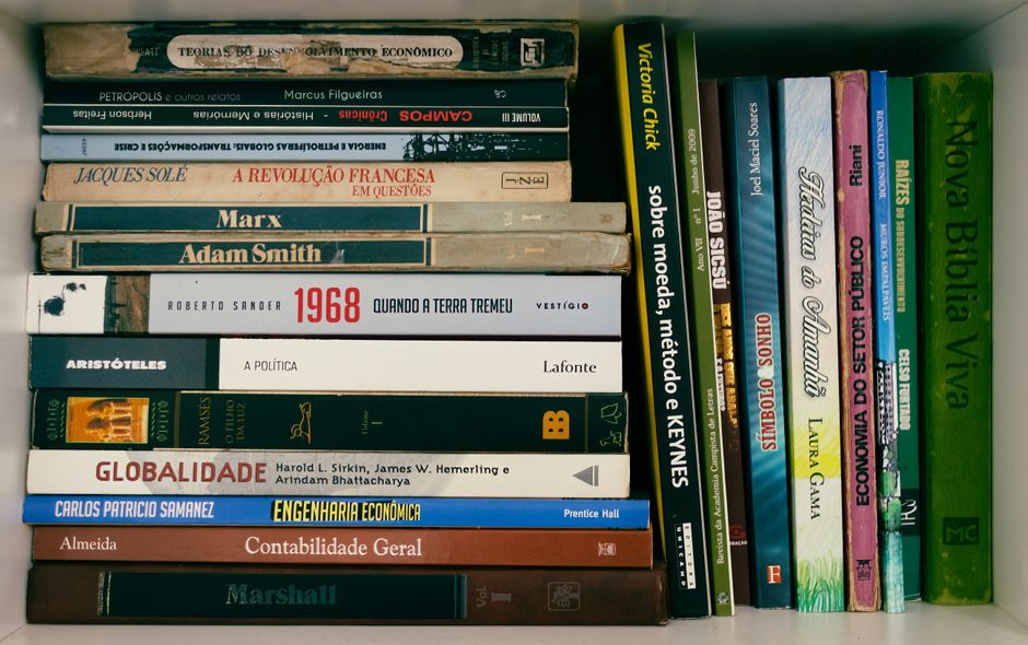 Imagem de uma estante com livros de economia, história e ciências sociais, voltada para estudos e pesquisa acadêmica.