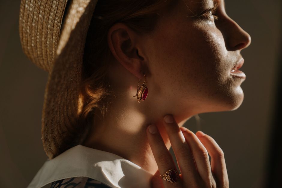 Mulher com rádio de sombrero, contemplando o pôr do sol com iluminação quente, em um momento de reflexão ao ar livre.
