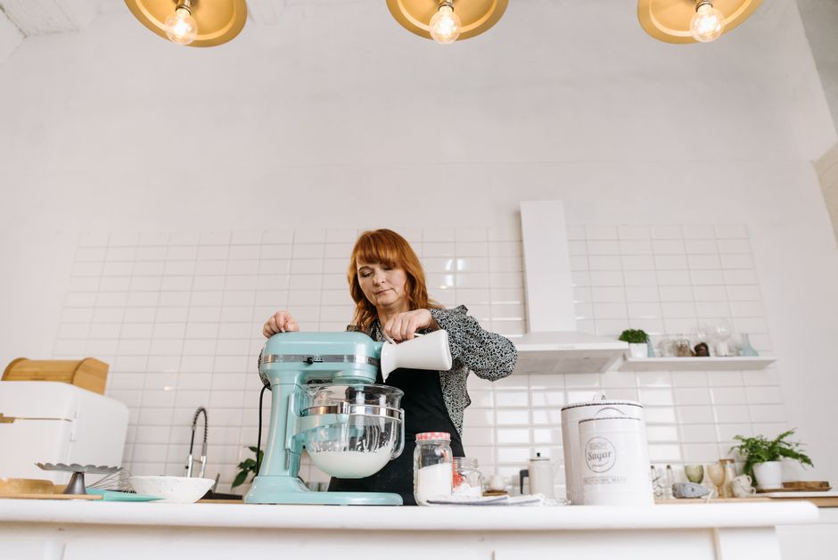 Mulher preparando ingredientes em uma cozinha moderna, em um momento de preparo culinário.