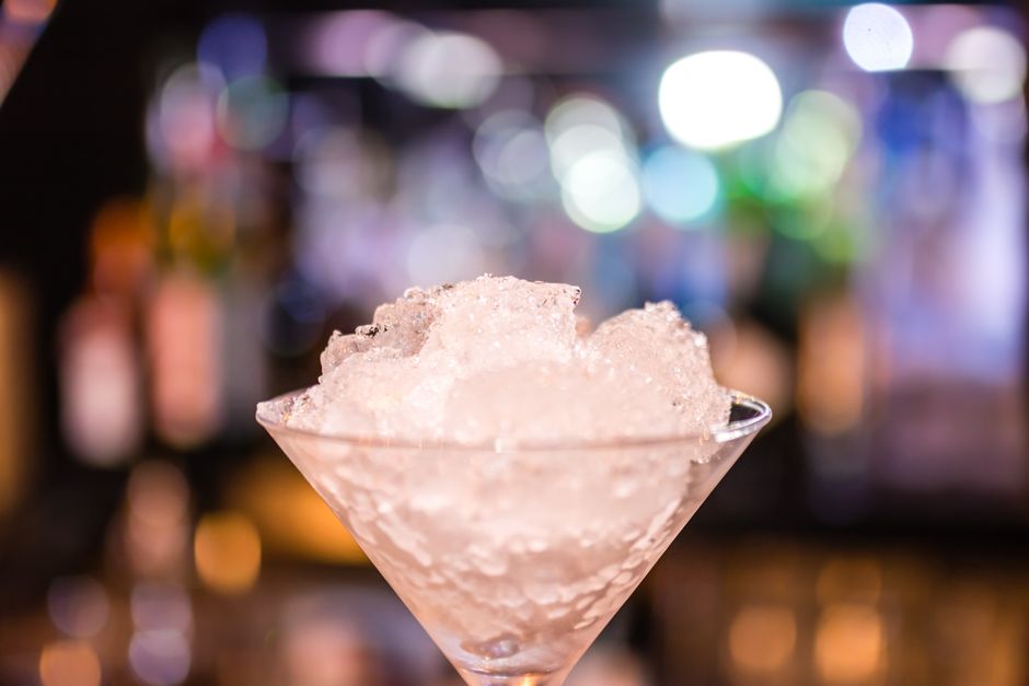 Imagem de um coquetel com gelo triturado em um ambiente de bar ou balada, ideal para ilustrar temas de bebidas e entretenimento noturno.