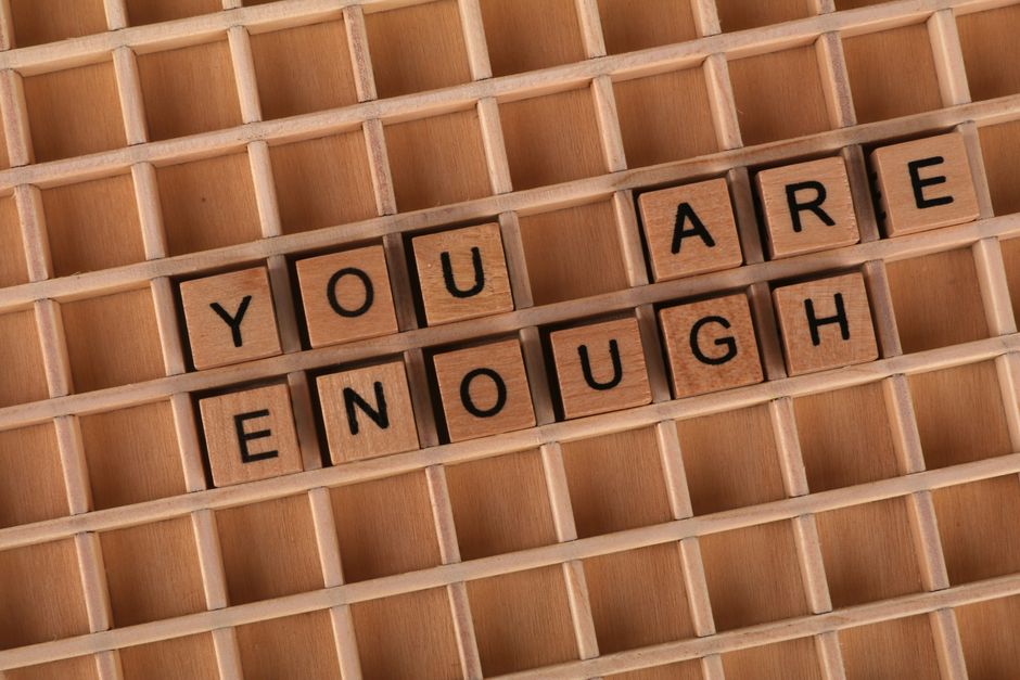 Imagem simbólica com blocos de madeira formando a frase 'You Are Enough', promovendo mensagem de autoestima e empoderamento pessoal.