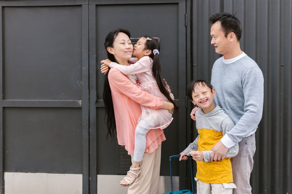Família feliz se reencontrando e demonstrando afeto ao exterior, simbolizando união e amor familiar.