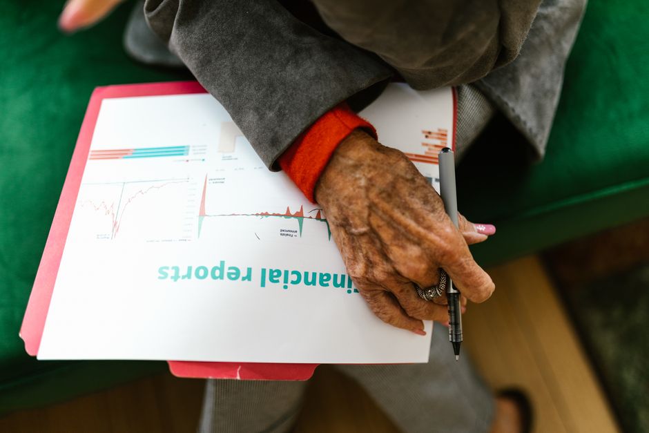 Pessoa idosa analisando relatórios financeiros e gráficos, evidenciando a importância da gestão de finanças na terceira idade.