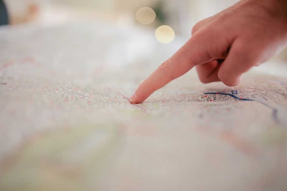 Pessoa apontando para um local específico em um mapa, simbolizando planejamento ou tomada de decisão.
