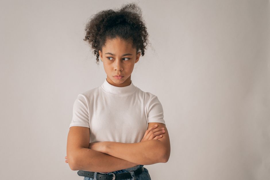 Jovem menina com expressão de descontentamento ou resistência, simbolizando questões relacionadas à educação, disciplina ou relacionamento infantil.