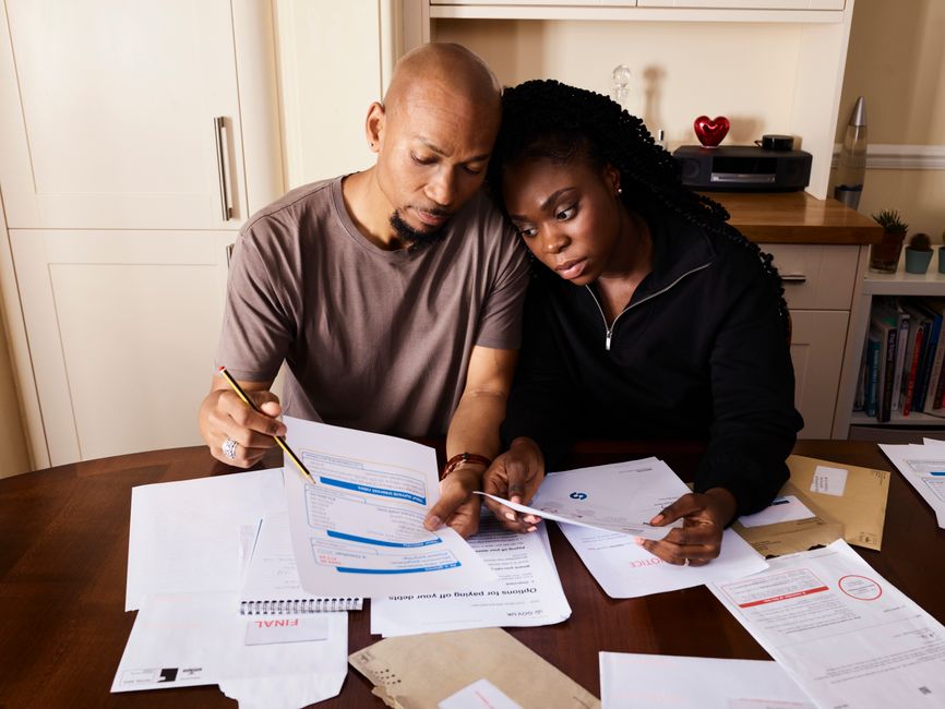 Casal analisando documentos de forma colaborativa, representando planejamento financeiro ou organização de contas pessoais.