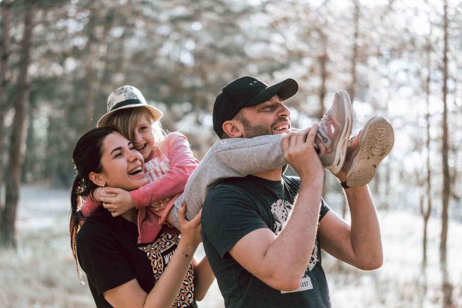 Imagem de uma família feliz brincando ao ar livre em meio à natureza, celebrando momentos de lazer e união.