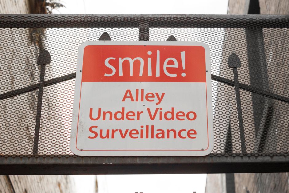 Sinal de aviso em uma passarela urbana alertando que o beco está sob vigilância por câmeras de vídeo.