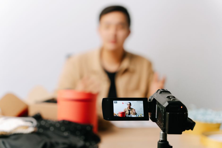 Pessoa sendo gravada em um vídeo de blog, com foco na produção de conteúdo digital e comunicação online.