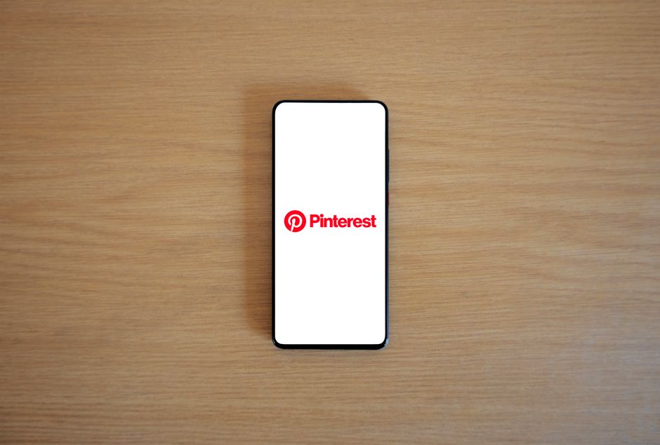 Imagem de um smartphone exibindo o logo do Pinterest, representando inspiração e pesquisa visual para blogs e criações digitais.