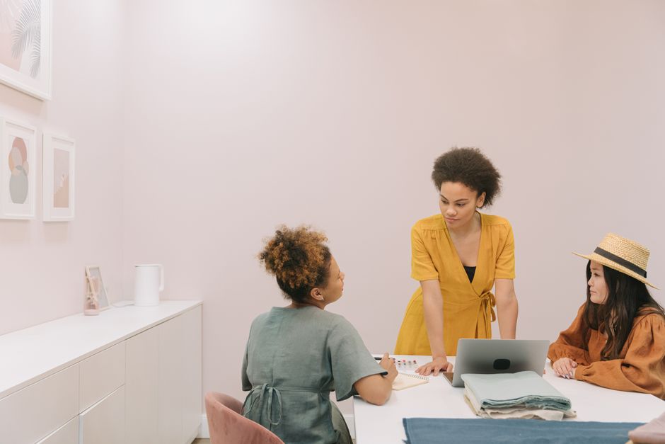 Mulheres em reunião de trabalho discutindo estratégias em ambiente de escritório moderno.