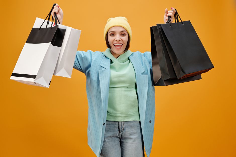 Mulher feliz segurando várias sacolas de compras, simbolizando sucesso nas compras e satisfação do cliente.