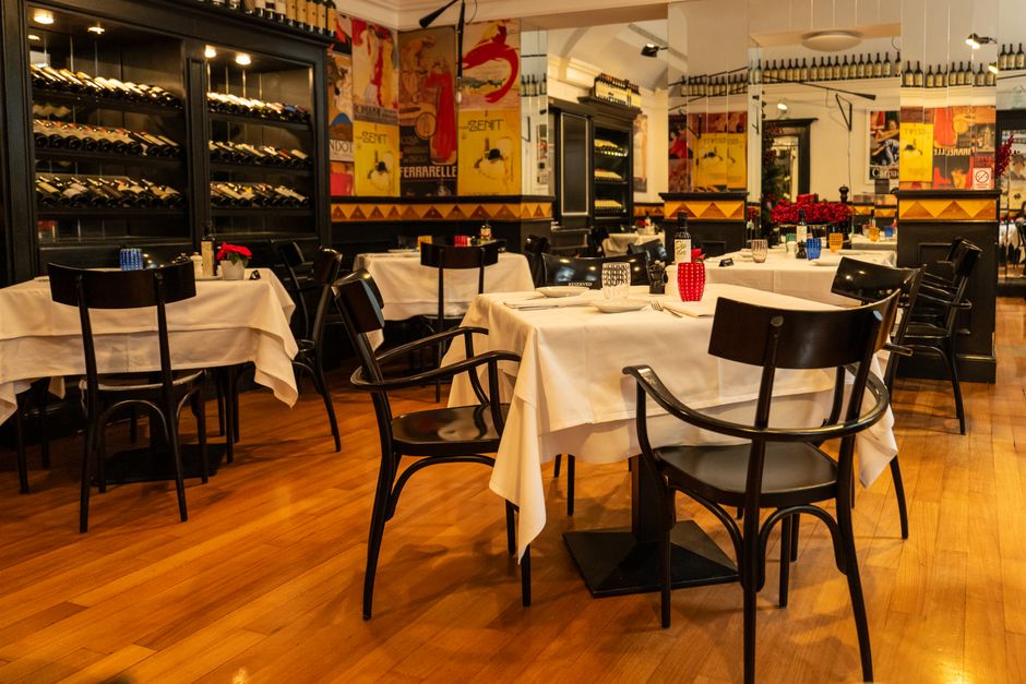 Sala de restaurante elegante decorada com mesas dispostas para refeições, com detalhes artísticos nas paredes e iluminação acolhedora.