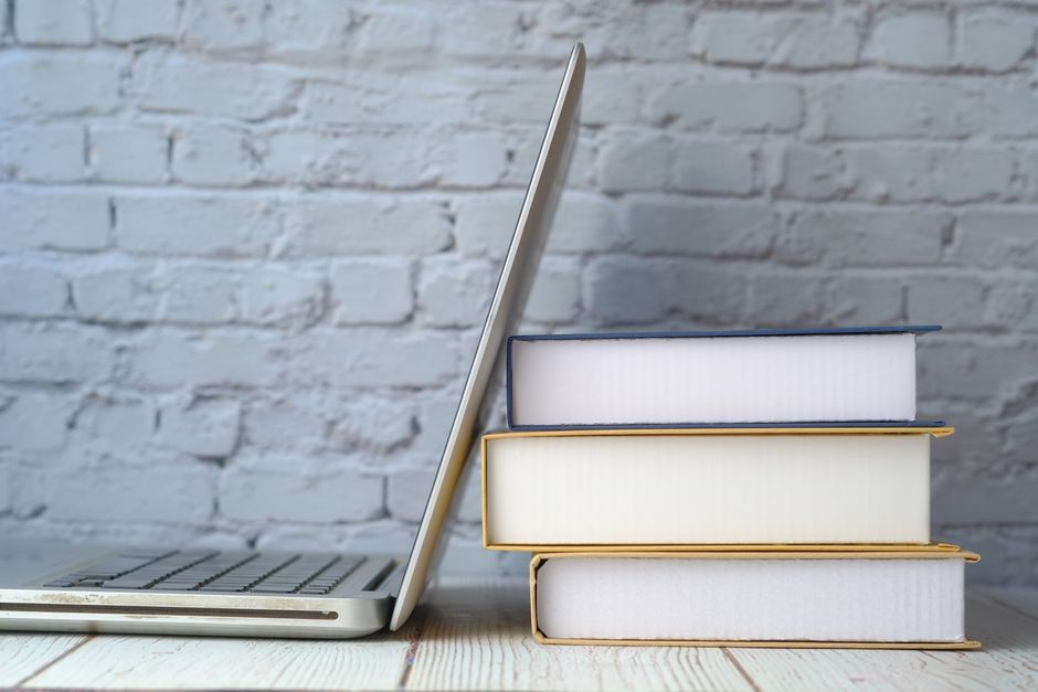 Imagem mostrando uma combinação de recursos de estudo com livros empilhados ao lado de um laptop, ideal para artigos sobre educação e pesquisa.