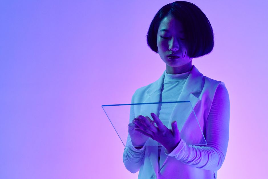 Mulher futurista interagindo com uma interface holográfica em um ambiente de tecnologia avançada, representando inovação digital.