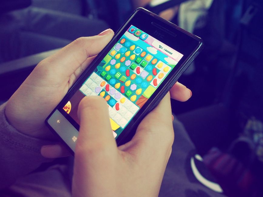 Pessoa jogando um jogo de with match no smartphone em um ambiente de lazer ou transporte.