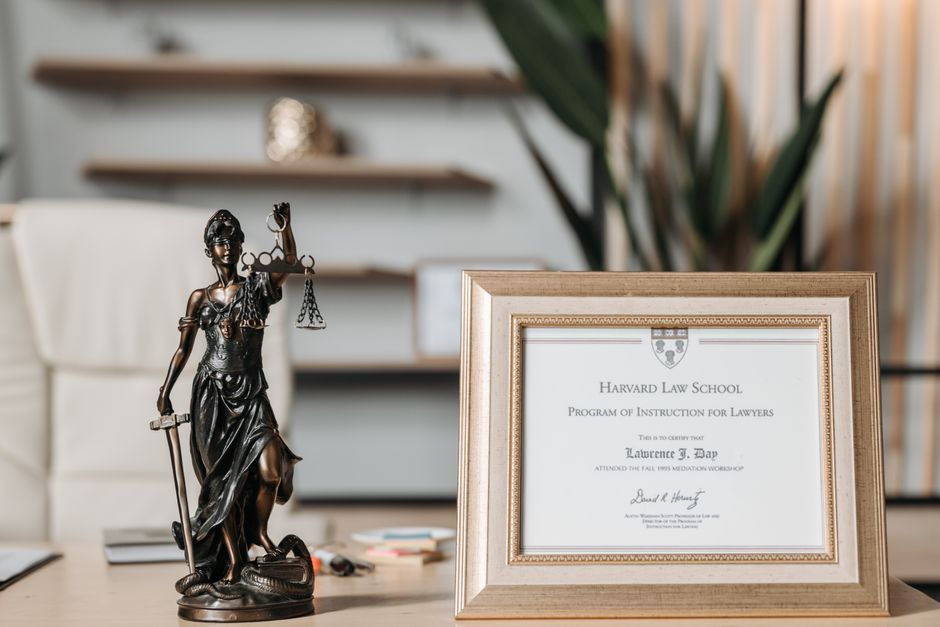 Imagem de um ambiente com uma escultura da Justiça, uma moldura com diploma de direito e uma cadeira, simbolizando o contexto acadêmico e profissional do direito.