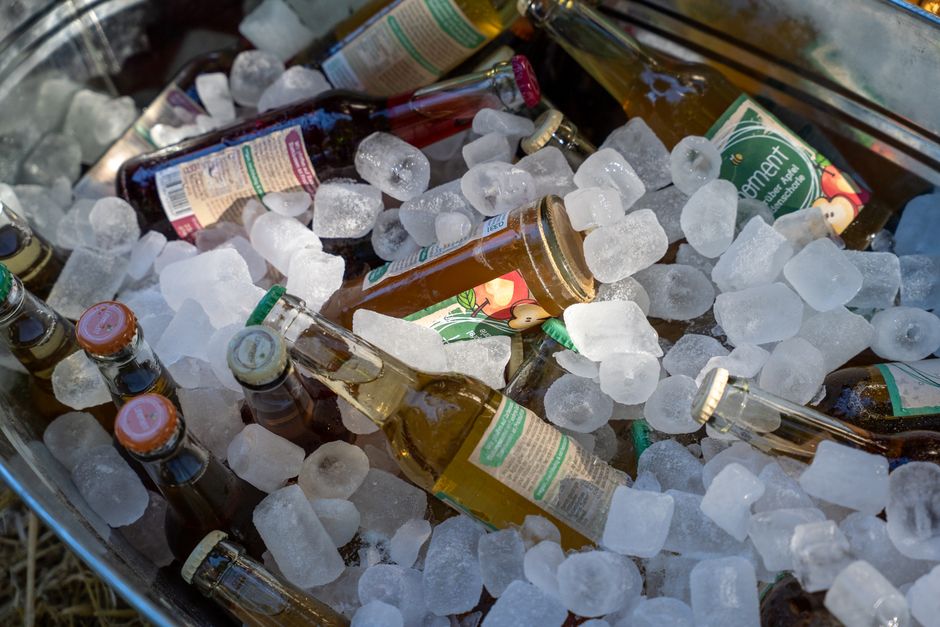 Imagem de garrafas de bebidas, como cerveja, em um recipiente com gelo, ideal para ilustrar consumo de bebidas em eventos ou festas ao ar livre.