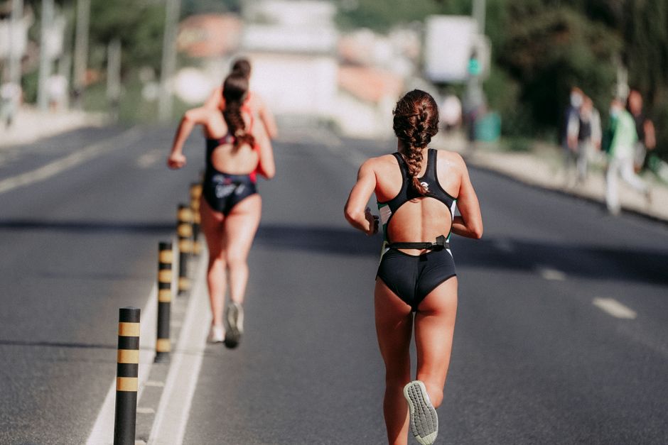 Duas mulheres competindo em uma corrida de rua, destacando o esporte e a determinação durante a atividade física ao ar livre.