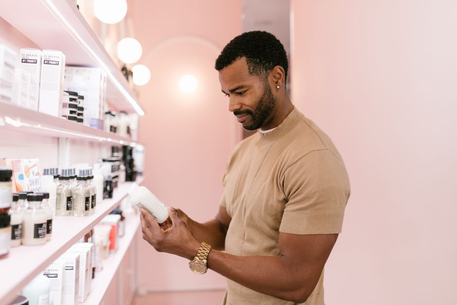 Homem analisando produto em uma farmácia ou loja de cosméticos, destacando consumo consciente ou avaliações de qualidade.