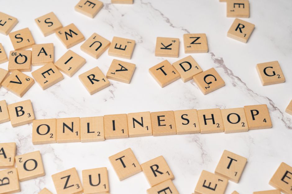 Imagem representando o tema de negócios online com peças de dominó formando a palavra 'ONLINE SHOP', sobre uma superfície de mármore clara.