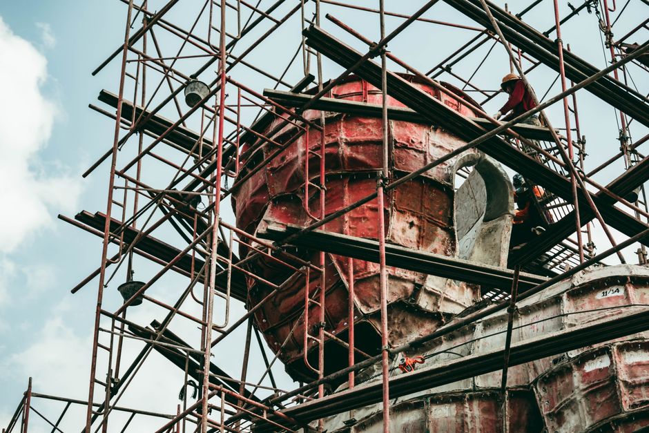 Imagem de uma estrutura de andaimes ao redor de um prédio em reforma ou construção, com foco na complexidade da engenharia civil.