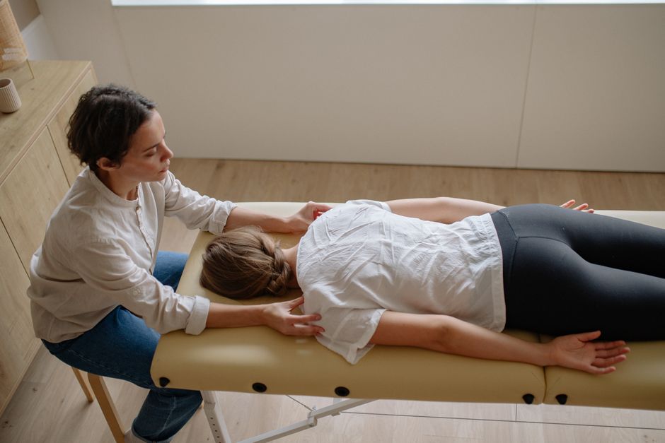 Imagem de uma sessão de massagem terapêutica com uma profissional cuidando de uma paciente deitada em uma maca, em ambiente de bem-estar e saúde.
