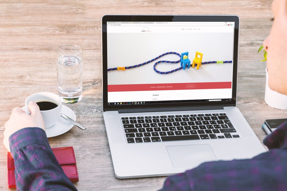 Pessoa trabalhando em um blog ou site de negócios com uma imagem de duas cadeiras de brinquedo e uma corda simbolizando conexão ou parceria na tela do laptop.