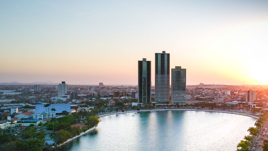 Vista de uma área urbana moderna com edifícios altos ao entardecer, destacando a integração entre natureza e arquitetura na cidade.