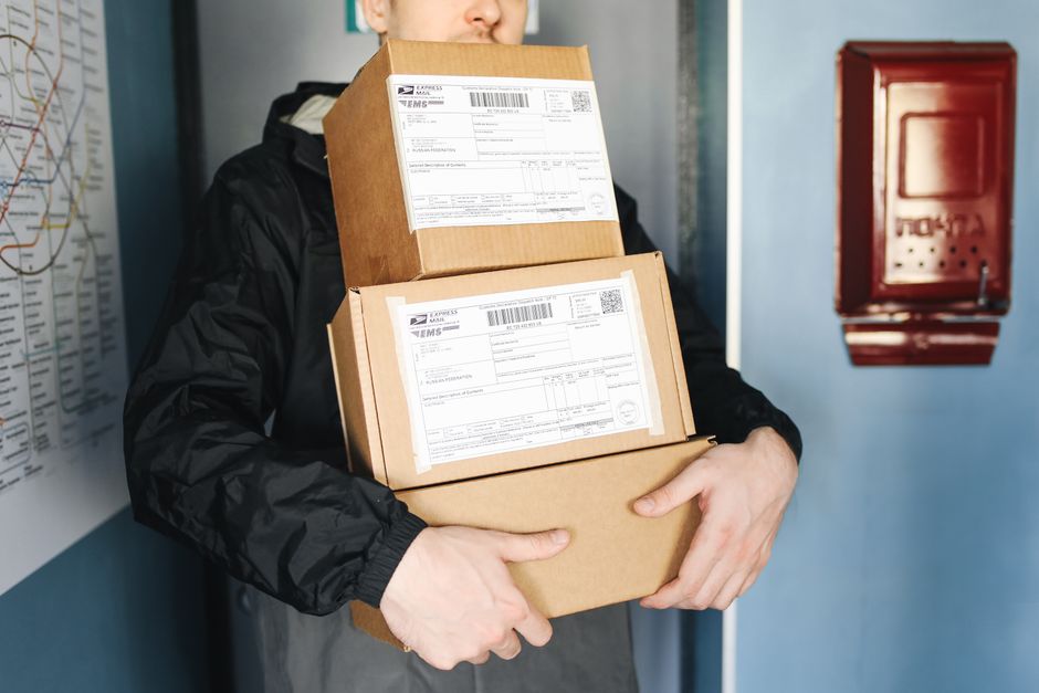 Pessoa carregando caixas com encomendas ou documentos, simbolizando entregas ou logística.