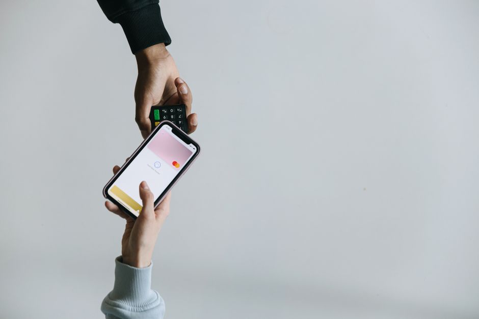 Pessoa realizando pagamento com cartão de crédito pelo celular em um ambiente minimalista.
