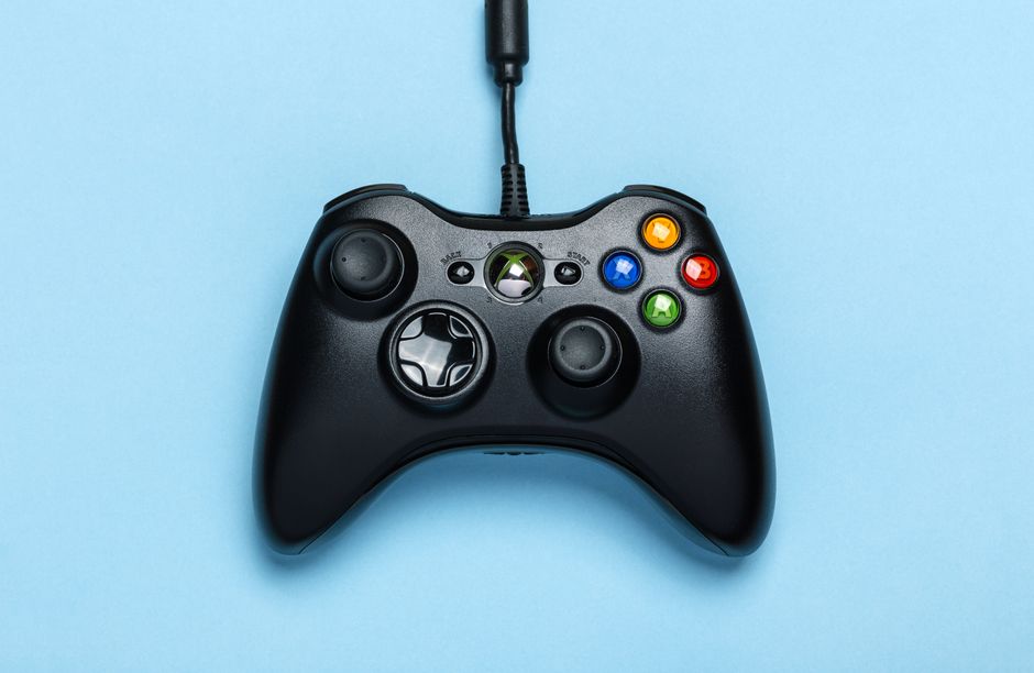Controle de videogame conectado por cabo sobre fundo azul, representando o tema de jogos eletrônicos e entretenimento digital.