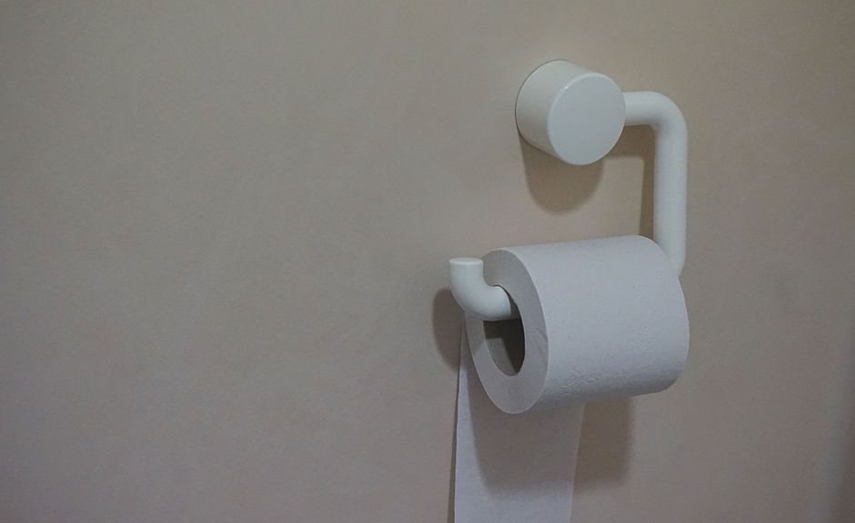Imagem de um suporte de papel higiênico moderno na parede de um banheiro, com foco na estética minimalista do item.