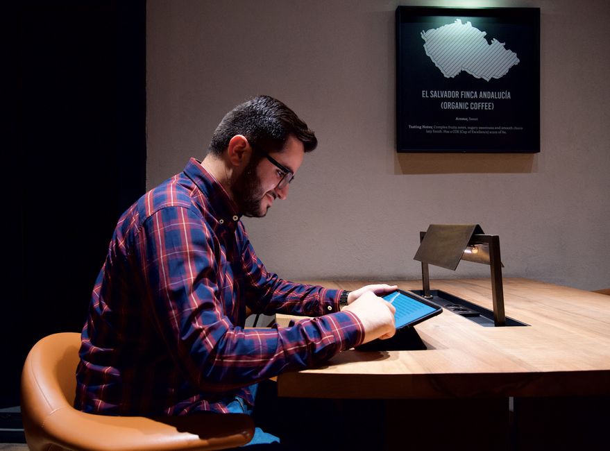 Homem estudando conteúdo em um ambiente de coworking ou biblioteca com foco em tecnologia ou inovação.