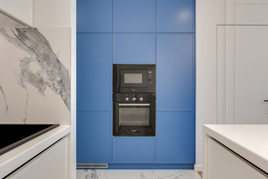 Imagem de uma cozinha moderna com destaque para armários azuis e eletrodomésticos embutidos, ideal para ilustrar ambientes contemporâneos e decoração de cozinhas.