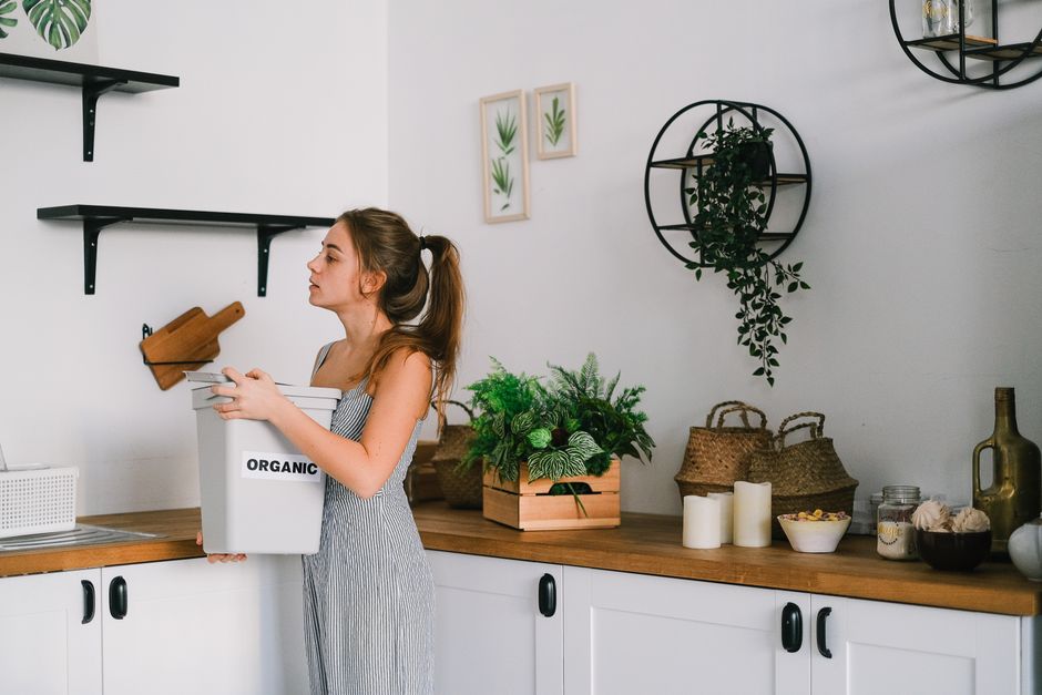 Mulher organizando alimentos orgânicos em uma cozinha moderna com decoração minimalista e plantas.