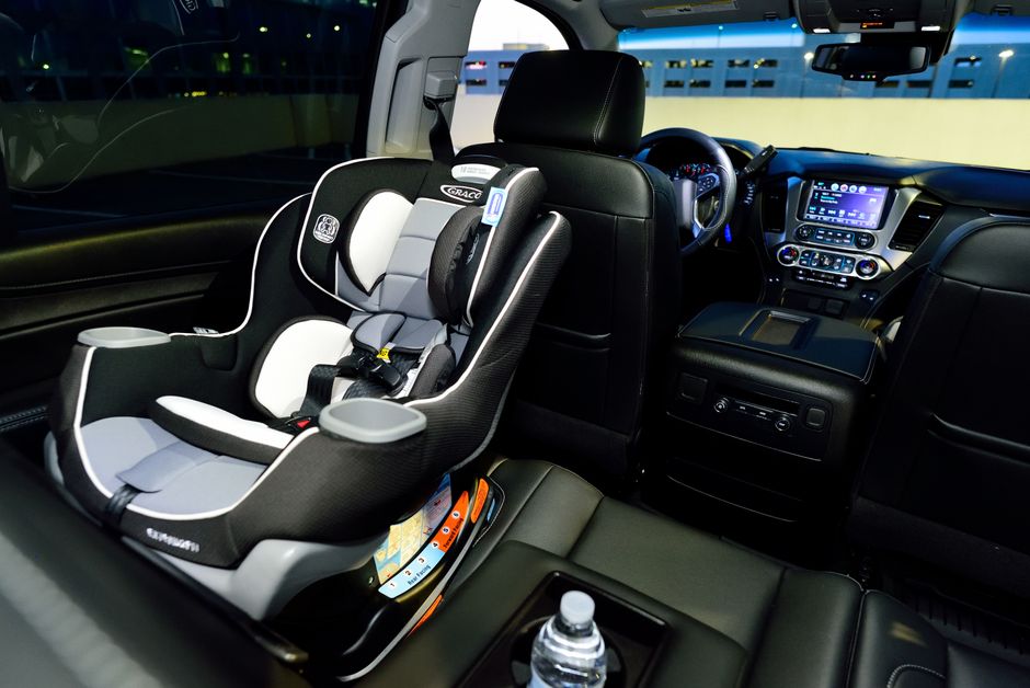 Interior de um veículo sofisticado equipado com uma cadeirinha de criança, destacando-se pela tecnologia e conforto para viagens seguras em família.