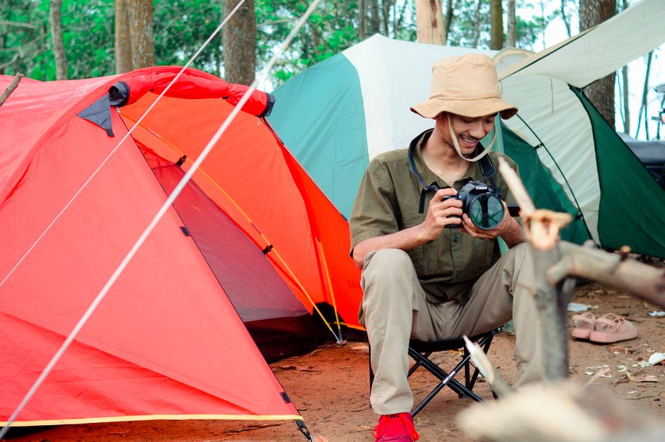 Homem em um acampamento na floresta, explorando a fotografia ao ar livre.