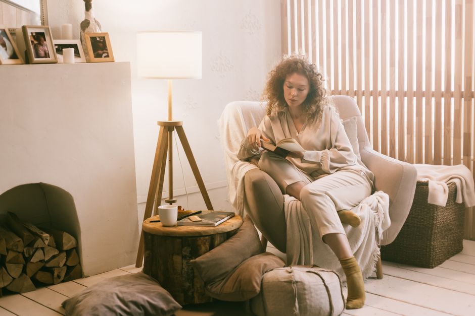 Mulher lendo um livro em um ambiente aconchegante, ideal para discutir a importância do descanso e bem-estar na rotina diária.