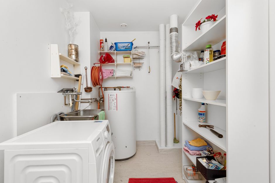 Lavanderia doméstica organizada com itens de limpeza, utensílios e eletrodomésticos brancos, em ambiente limpo e bem arrumado.