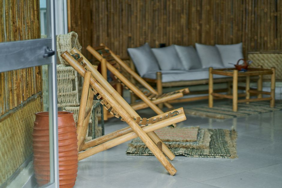 Imagem de um espaço de relaxamento com cadeiras de madeira, almofadas e decoração rústica em ambiente interno/externo aconchegante para momentos de descanso e lazer.