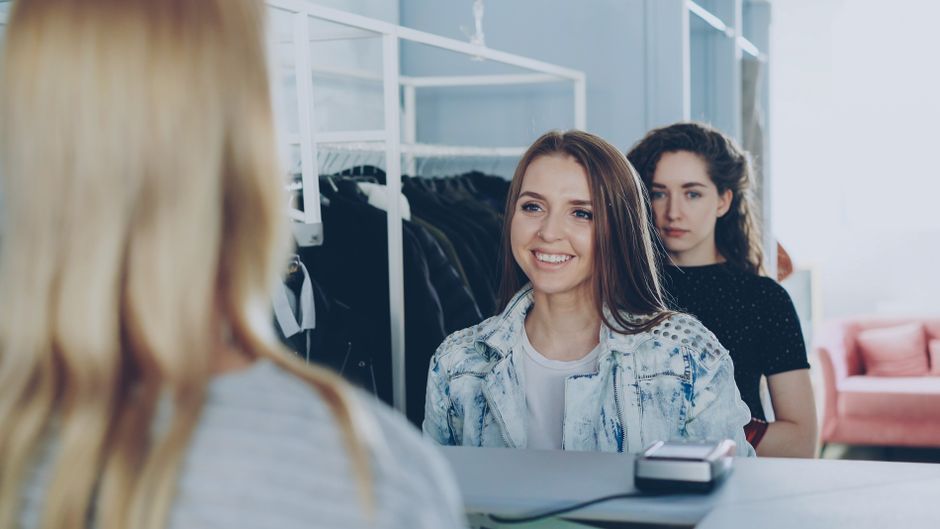 Mulheres em uma loja de roupas participando de uma conversa amigável na área de atendimento ao cliente.