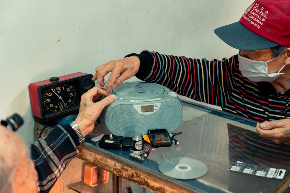 Pessoa trocando a fita de um rádio portátil em um ambiente doméstico, transmitindo nostalgia e conexão com o passado musical.